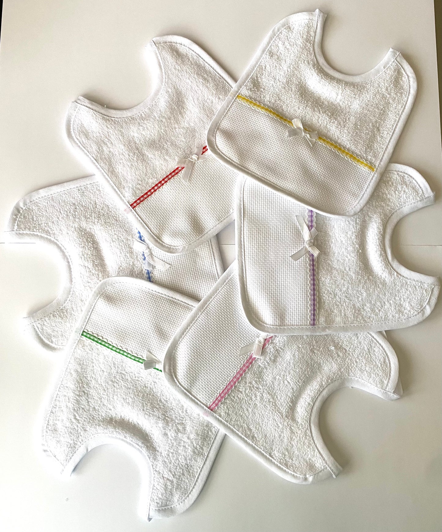 DA RICAMARE. CONFEZIONE N.6 BAVETTE IN SPUGNA BIANCA, INSERTO IN TELA AIDA CON BORDATURA DI VARI COLORI - Eccomi OnLine